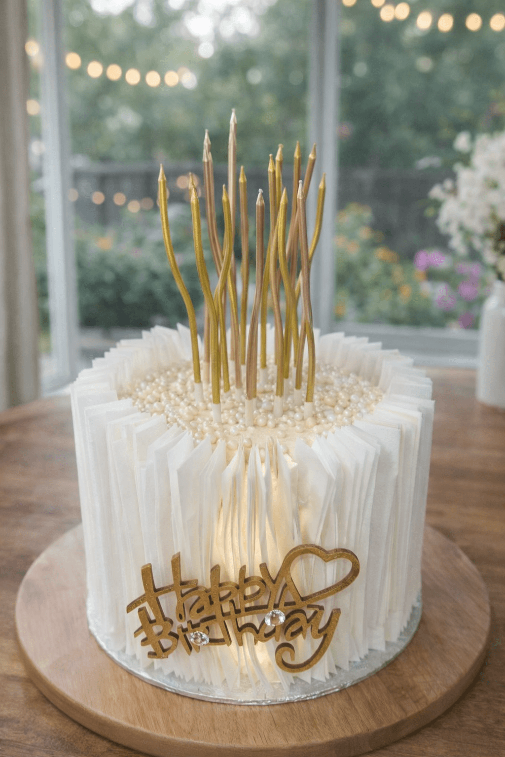A white birthday cake with tall gold candles